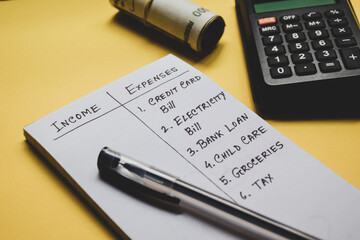 Monthly income and expenses list on yellow background with calculator and banknotes. Financial...