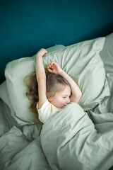 A little girl lies in bed and is sick, feeling unwell and having a cold in the winter