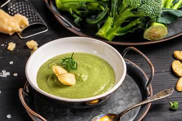 Healthy broccoli green cream soup in bowl over light background. Long banner format, top view. Diet detox food concept