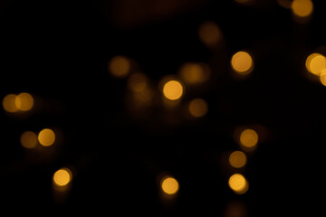 Defocused bokeh lights on black background, an abstract naturally blurred backdrop for Valentine's Day or birthday party. Festive light texture. Pink and red garland in blur. Overlay effect for design