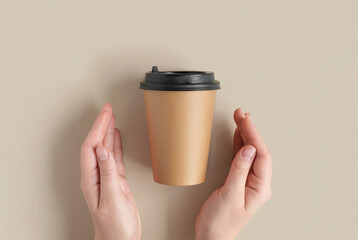 Top view of a Brown coffee paper cup. Mockup with lid. Human Hands with paper cup for coffee or tea on beige background. Flat lay. Zero waste, plastic free concept. Disposable Recycled cups