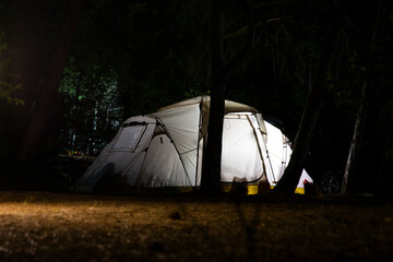 Illuminated tourist tent in the summer camp  at night. Glowing camping tent in the wood.