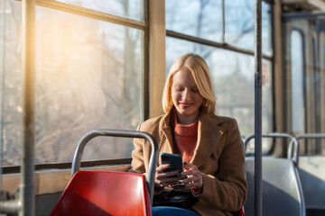 Modern smiling cute woman sitting in a bus . Smiling and looking away. Bus journey. Woman using her...