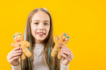 A cute girl holds in her hands two cookies in the form of a man. Funny teenager. Schoolboy