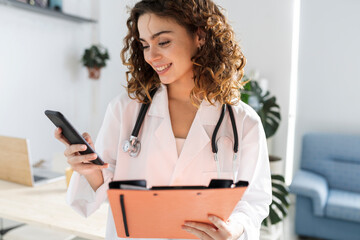 female doctor in consultation with folder and mobile phone - Powered by Adobe