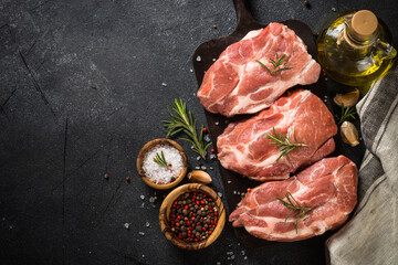 Fototapeta na wymiar Raw meat. Fresh steaks with herbs and spices at black background. Top view.