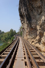 Fototapeta na wymiar Tracks of Thai Burma Railway (Death Railway) winding along the steep shore of River Kwae Noi on Tham Krasae Bridge (vertical image), Kanchanaburi, Thailand