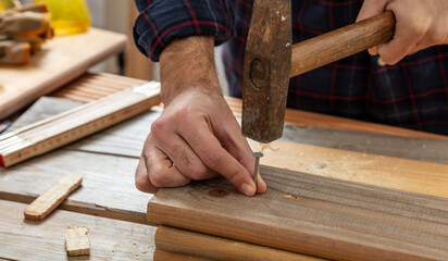 DIY, home repair and fixCarpenter nail wood. Male hand hold hammer and nail.