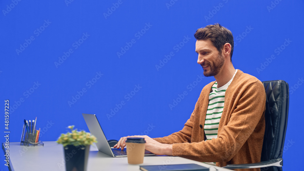 Poster green screen office background: caucasian businessman sitting at his desk working on a laptop comput