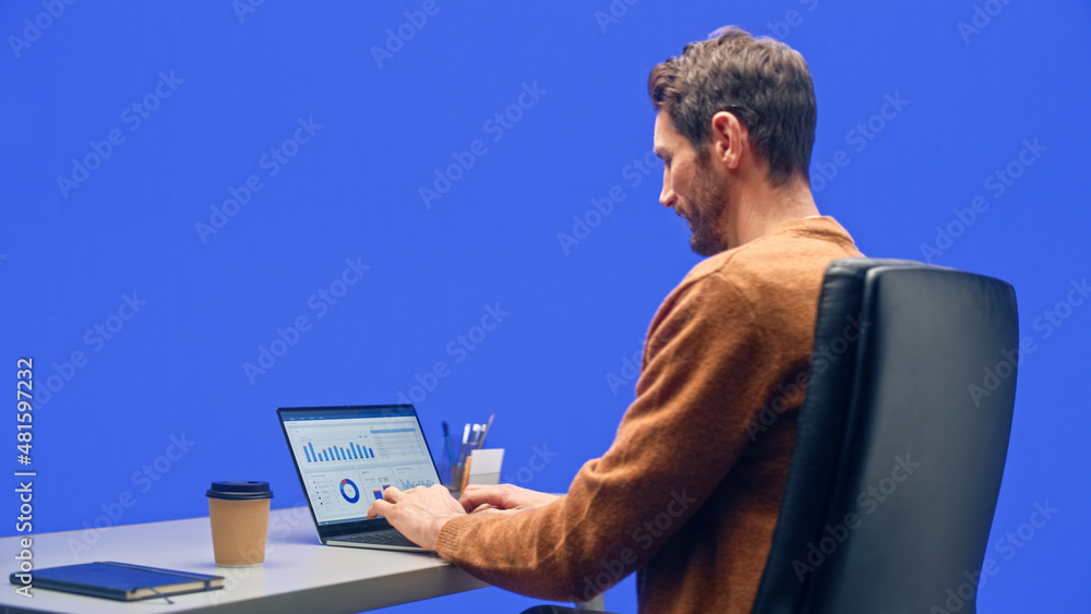 Poster green screen office background: caucasian businessman sitting at his desk working on a laptop comput