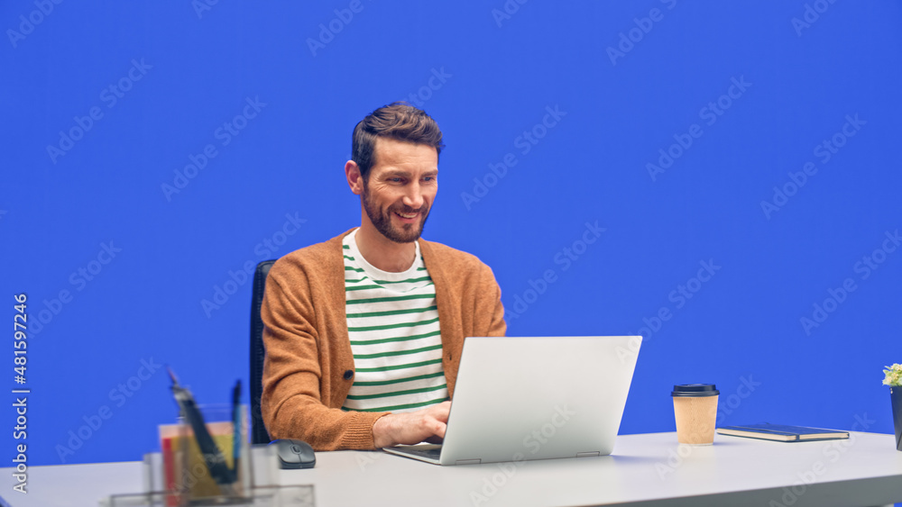 Poster green screen office background: caucasian businessman sitting at his desk working on a laptop comput