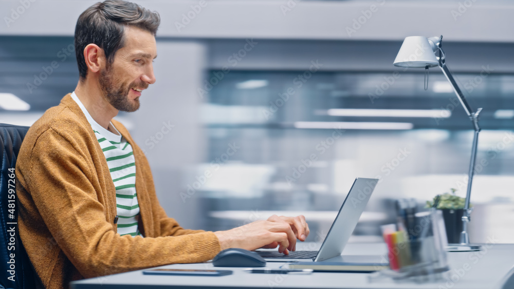 Poster Modern Office: Handsome Businessman Sitting at His Desk Working on a Laptop Computer. Man working with Big Data e-Commerce Analysis. Motion Blur Background Showing Active Work Day.