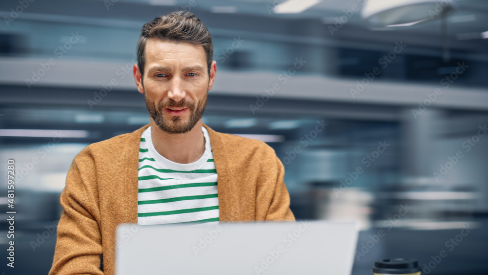 Poster Modern Office: Handsome Businessman Sitting at His Desk Working on a Laptop Computer. Man working with Big Data e-Commerce Analysis. Motion Blur Background Showing Active Work Day.