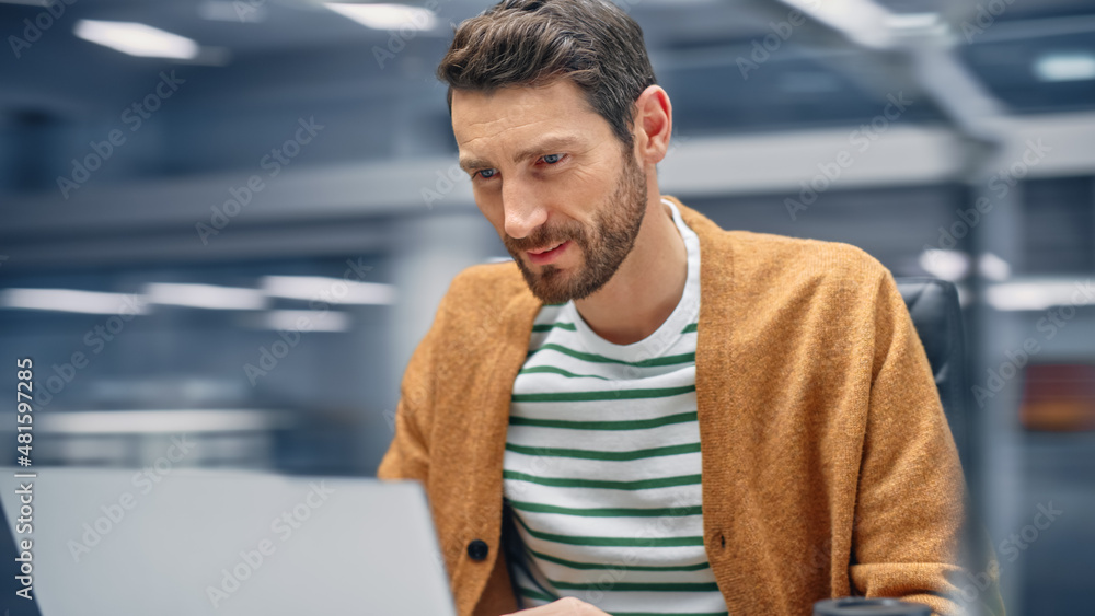 Aufkleber Modern Office: Handsome Businessman Sitting at His Desk Working on a Laptop Computer. Man working with Big Data e-Commerce Analysis. Motion Blur Background Showing Active Work Day.