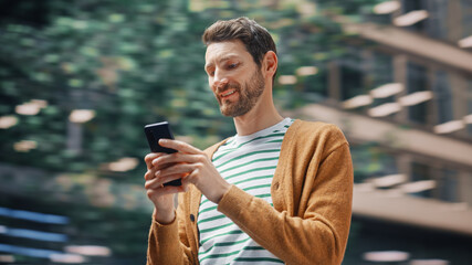 Street Shot: Portrait of Caucasian Man Using Smartphone in the Big City. Creative Professional Using Mobile Phone App for e-Commerce Online Shopping. Blurred Background.