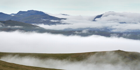 The summits of Skafell Pike Great End on the left with Lingmell on the right sticking out of a cloud inversion from below the summit of Raise in the English Lake District, England, UK.