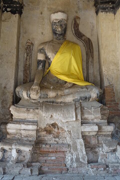 Ancient Buddha statue with yellow fabric mantle at Wat Chai Watthanaram temple, Ayutthaya, Thailand (vertical image)