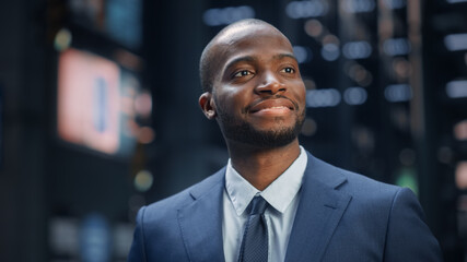 Portrait of Thoughtful Black Businessman wearing Suit, Standing in the Big City Business District Street, Posing and Smiling. Successful African American Digital Entrepreneur