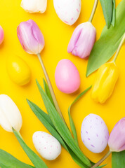 Easter greeting card. Multicolored easter eggs and tulips on yellow background. Easter concept