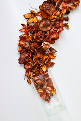 dried rose petals on a white background.dried petals in color are scattered on the table.a vase and dried rose petals in color on a white background.liaists in color close-up
