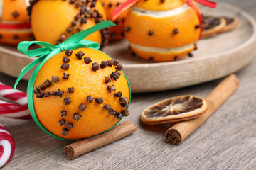 Pomander balls made of tangerines with cloves on wooden table, closeup