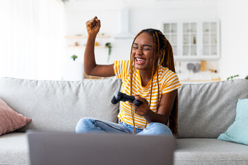 Emotional african american woman playing video games on laptop © Prostock-studio