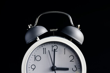 Time concept. White alarm clock in dark background with copy space.
