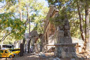 Ruins of the aqueduct of the ancient ancient city of Phaselis illuminated by the bright sun in Pine forest, woods in sunny weather in Turkey, Antalya, Kemer. Turkey national nature landmarks.