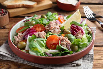 Plate of delicious salad with canned tuna and vegetables served on wooden table