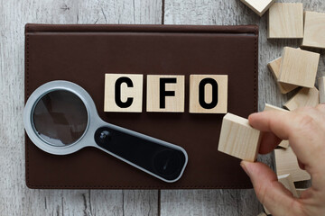 CFO chief financial officer wooden blocks on brown notebook top view on wooden background
