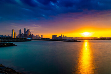 Fototapeta premium Dramatic sunset sky with clouds. Beautiful sunset over the Arabian sea in Dubai Marina UAE. Nature and beauty concept. Orange sundown. Long Exposure Shot.