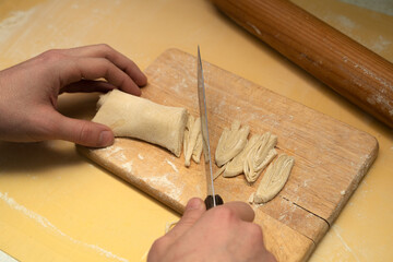 Cooking homemade noodles. A young man cuts rolled dough into thin strips of noodles. The concept of healthy eating.
