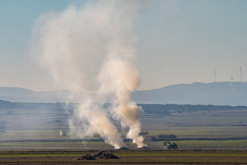 Smoke from burning agricultural debris is seen in a field.