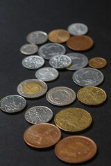 Coins of different countries. A scattering of coins on a black background. Shallow depth of field