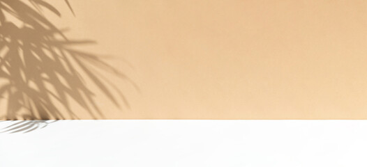 Minimal abstract background for the presentation of a cosmetic product. Premium podium with a shadow of tropical palm leaves on a beige wall and white table. Showcase, display case. Banner