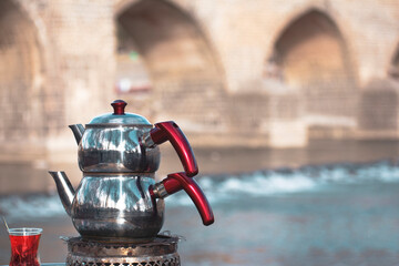 Turkish black tea and teapot in Diyarbakir historical bridge view
