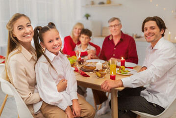 Portrait of happy multi generation family sitting at festive table, looking at camera and smiling