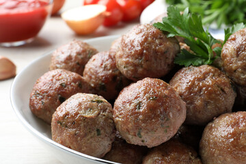 Tasty cooked meatballs and parsley on table, closeup view