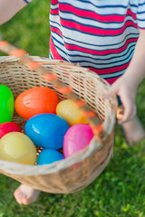 Fototapeta na wymiar Plastic multi-colored Easter eggs close-up in wicker basket is held by child...