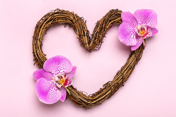 heart shaped rattan wreath decorated with tropical flowers of orchid on pink background Top view Flat lay Holiday card Happy Valentine's day, love concept Copy space