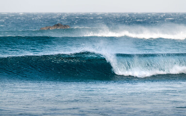 Naklejka premium Small set of waves breaking on the beach forming a tube. Beautiful blue ocean water
