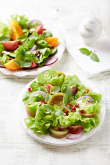 Salad with red and yellow Tomatoes and Pomegranate Seeds on bright wooden Background. Close up. 