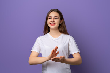 Portrait of happy brunette girl laughing, clap hands and looking pleased, applause to praise you, complimenting, standing in blank white t shirt over purple background