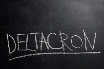Fototapeta premium A close-up of the word Deltacron written in white chalk on a black board and underlined. Deltacron is a new version of Covid-19. Place to insert text.