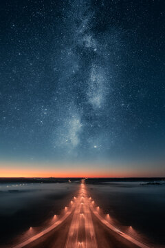 Epic view of highway at night with beautiful stars and milky way in the sky. Transportation background.