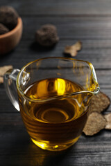 Fresh truffle oil in glass jug on black wooden table