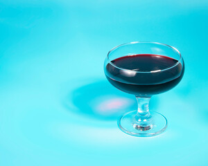 Red wine in glass on blue background with copy space