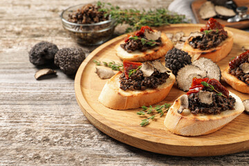 Delicious bruschettas with truffle sauce and sun dried tomatoes on wooden table. Space for text