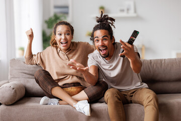 Overjoyed young african american couple celebrating goal while watching football match together