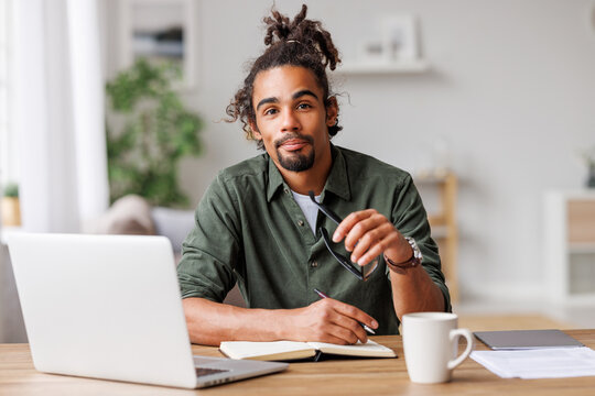 Young african american man freelancer working remotely on laptop or studying online at home